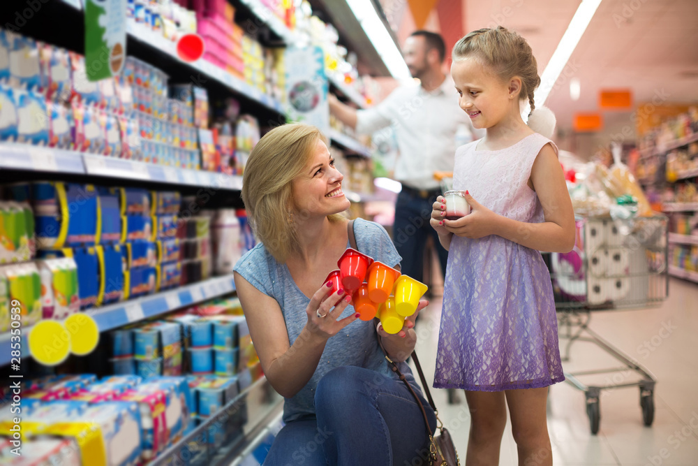 Portrait of  woman and girl holding package with yogurt in grocery shop