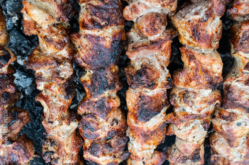 Frying pork on a skewer over a brazier. Turning meat over coals. Appetizing shish kebab.