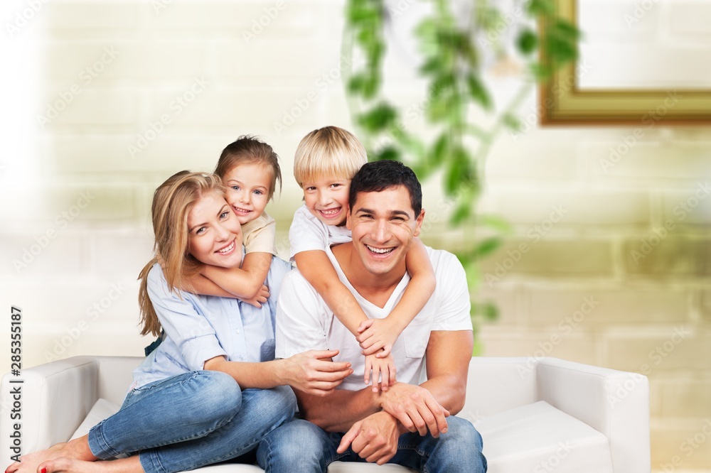 Beautiful smiling family sitting at sofa at home