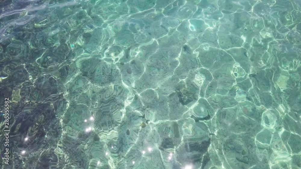 Sea Surface Ripple at Sunlight with Transparent Clear Water and Visible Sandy Bottom with Underwater Rocks. Aerial Top View Sea Surface Ripple at Sunlight with Transparent Clear Water and Visible Sandy Bottom with Underwater Rocks. Aerial Top View