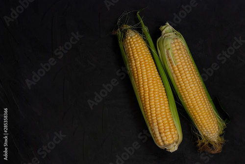 Yellow sweet raw corn on a black background.