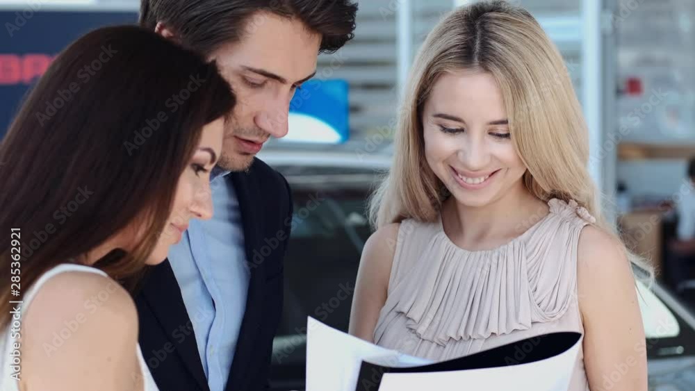 business couple signing an agreement to purchase a new car for their company business couple signing an agreement to purchase a new car for their company