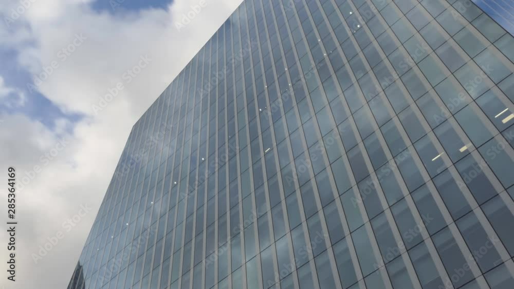 Time lapse. Moving clouds reflected on a high raise glass building.