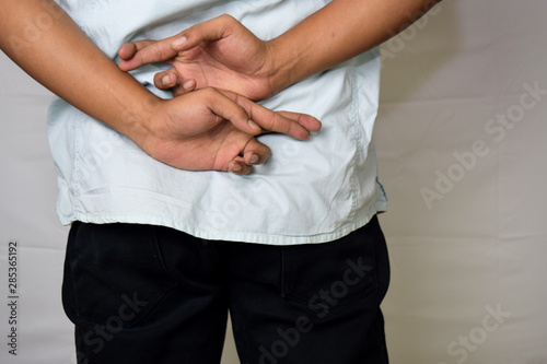 Close up Asian man shows his crossed finger behind isolated on white background