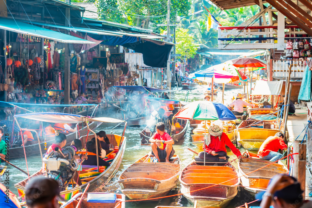 Naklejka premium Pływający targ Damnoen Saduak, turyści odwiedzający łódkę, położony w Bangkoku w Tajlandii.