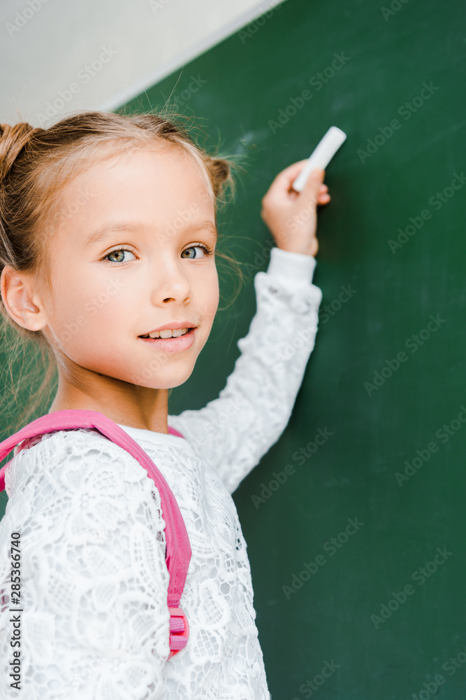 selective focus of happy schoolkid holding chalk