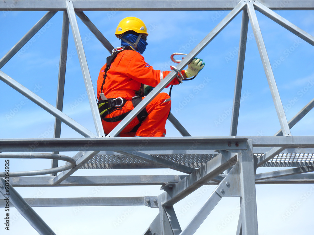 Man Working on the Working at height. Professional industrial climber in helmet and uniform works at height. Risky extreme job. Industrial climbing at construction site.   