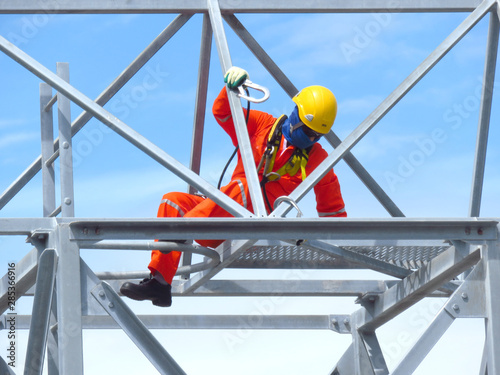 Man Working on the Working at height. Professional industrial climber in helmet and uniform works at height. Risky extreme job. Industrial climbing at construction site. 