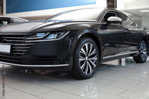 New luxury black car in modern auto dealership, closeup © New Africa