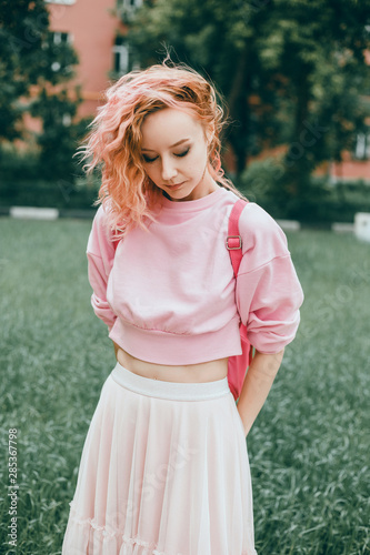 Young brunette girl in black standing outside and watching the sunset in the city, the sun shines brightly, fashionable clothes on a girl, hipster style,, tattoo, street, freedom, pink color, moodl photo