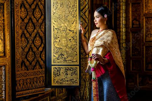 Beautiful women Thai girl holding hand Jasmine garland in traditional thai costume with temple ayutthaya is texture gold, identity culture of Thailand.