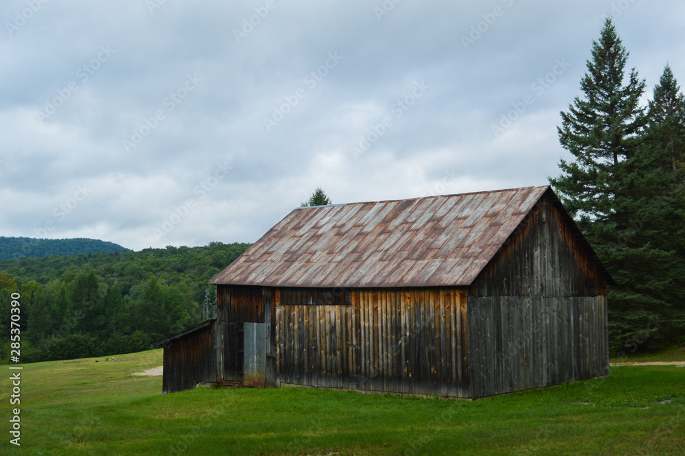 Weather-worn cedar barn overlooking the landscape in the Adirondack Mountains under a troubled sky