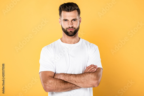 handsome man in white t-shirt with crossed arms isolated on yellow