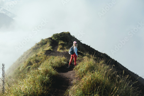 pretty woman posing in volcano, blue sky, hair wild, victory hand up!, outdoor portrait hipster, fashion model, pretty female, denim shorts, hippie, tattoo, hipster girl, Bali, denim shorts,cute 