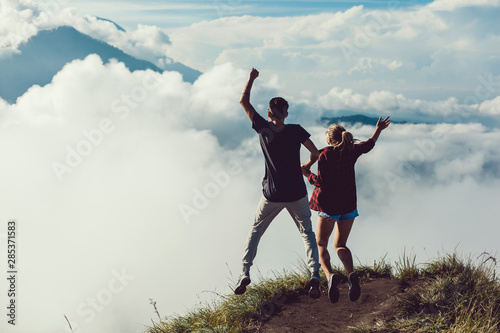 Hikers with backpacks relaxing on top of a hill and enjoying view of sunset in ocean. Island Lombok  Indonesia. Traveling along mountains and coast  freedom and active lifestyle concept