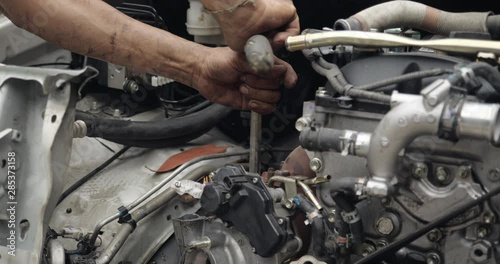 Auto mechanic working on car engine in mechanics garage. car service, repair, maintenance and people concept