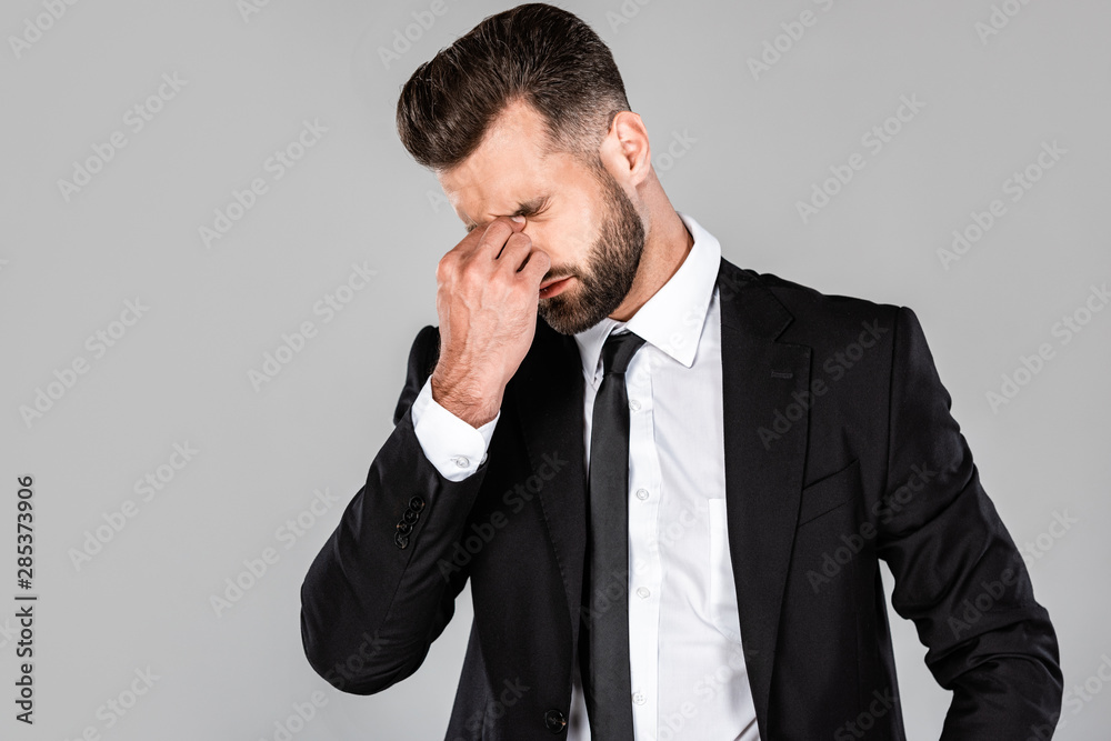 tired successful businessman in black suit rubbing his eyes isolated on grey tired successful businessman in black suit rubbing his eyes isolated on grey
