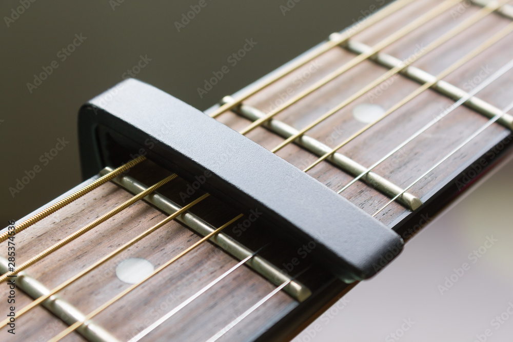 Black Capo on Acoustic Guitar String and Fingerboard Black Capo on Acoustic Guitar String and Fingerboard
