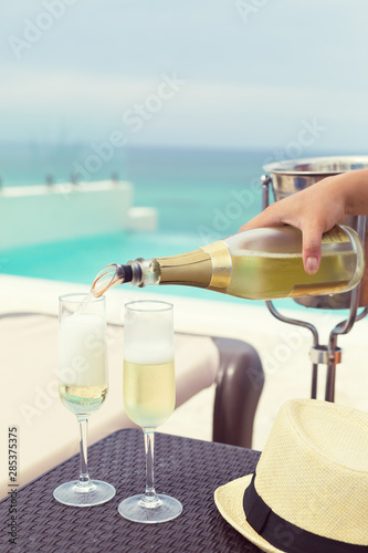 Pouring sparkling wine into a glass near swimming pool