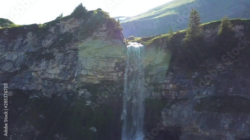 Gorgeous scenic ascending rising view of a waterfall in the mountains against the sun in the background on a beautiful sunny day in sulseewli switzerland photo