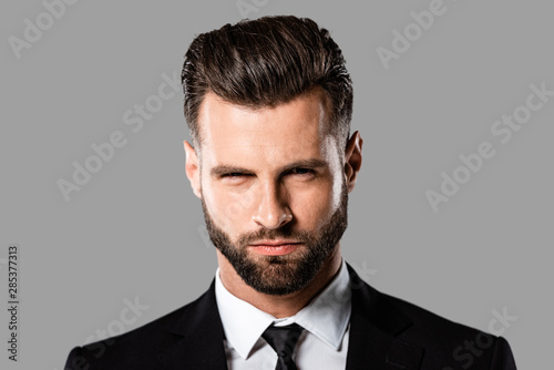 portrait of angry handsome businessman in black suit isolated on grey © LIGHTFIELD STUDIOS