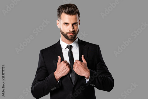 handsome stylish businessman in black suit isolated on grey