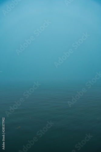 Outside nature photo featuring fog over a calm sea in the morning.