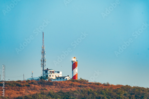 Lighthouse and signal tower on a mountain top with blue sky background. photo