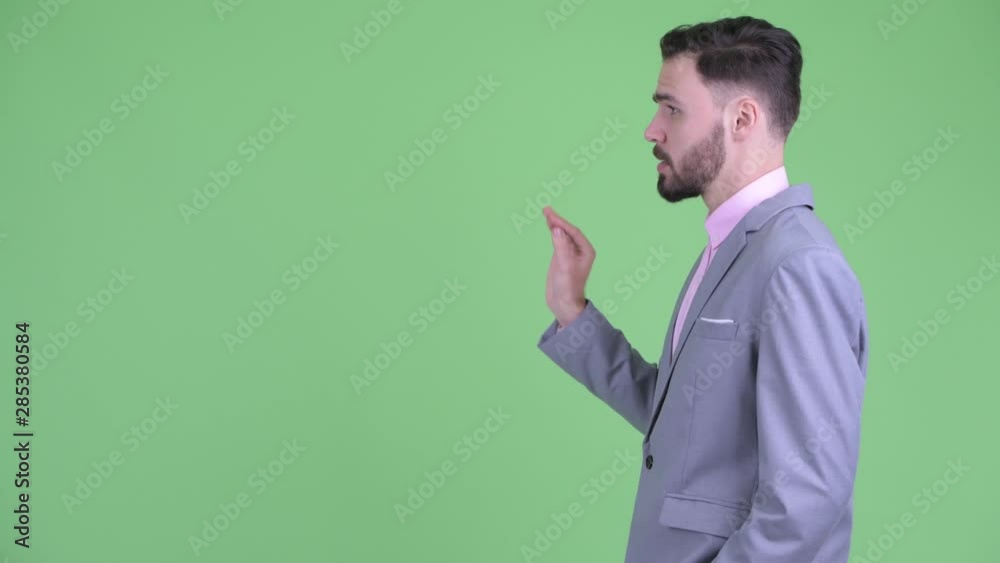 Profile view of happy young bearded businessman talking Profile view of happy young bearded businessman talking