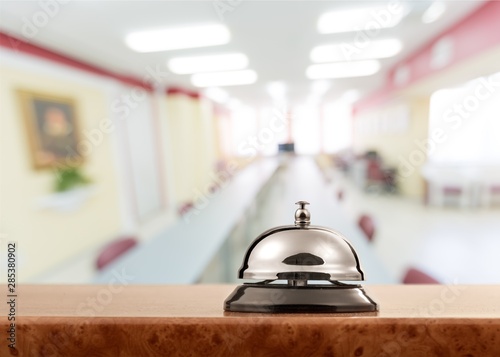 Vintage hotel reception service desk bell on wooden table with office background