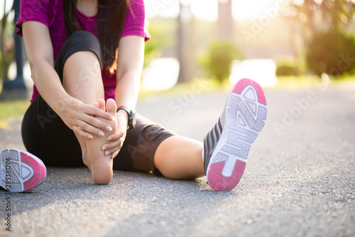 Young woman massaging her painful foot while exercising. Running Sport and excercise injury concept.