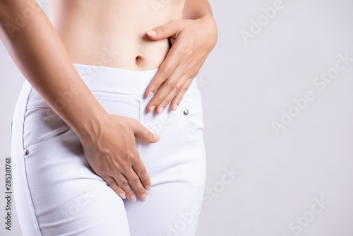 Young woman having painful stomachache with hands holding pressing her crotch lower abdomen. Medical or gynecological problems, healthcare concept