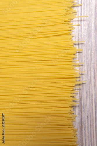 raw spaghetti pasta scattered on wooden table, close-up view from above