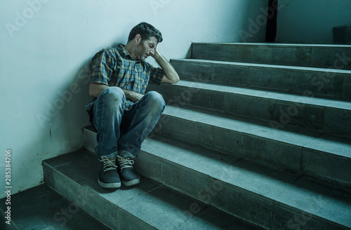 desperate man sitting outdoors on dark grunge street corner staircase feeling sick suffering depression problem and anxiety crisis in mental health concept