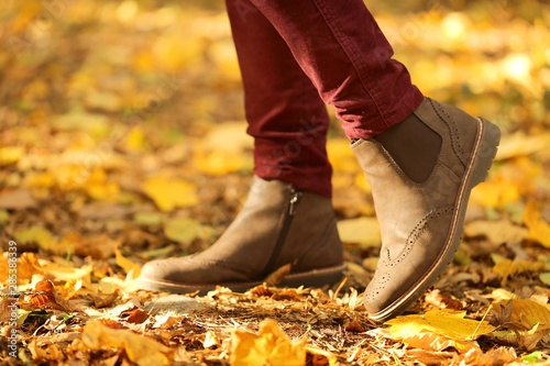 Autumn time. Autumn shoes . Female legs in brown boots on yellow maple leaves. Fall season.