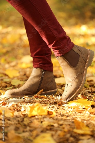 Autumn time. Autumn shoes . legs in brown boots on yellow maple leaves. Fall season.