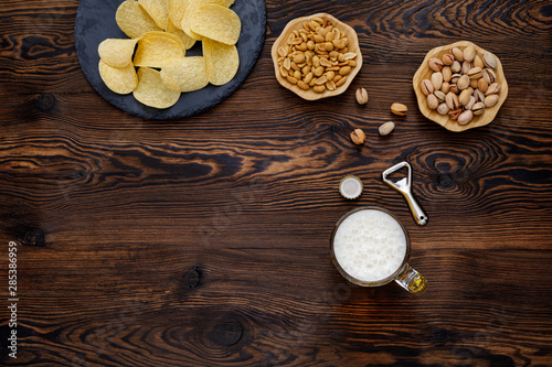 Beer glass with bottle cap and snack on wood background. top view. copy space