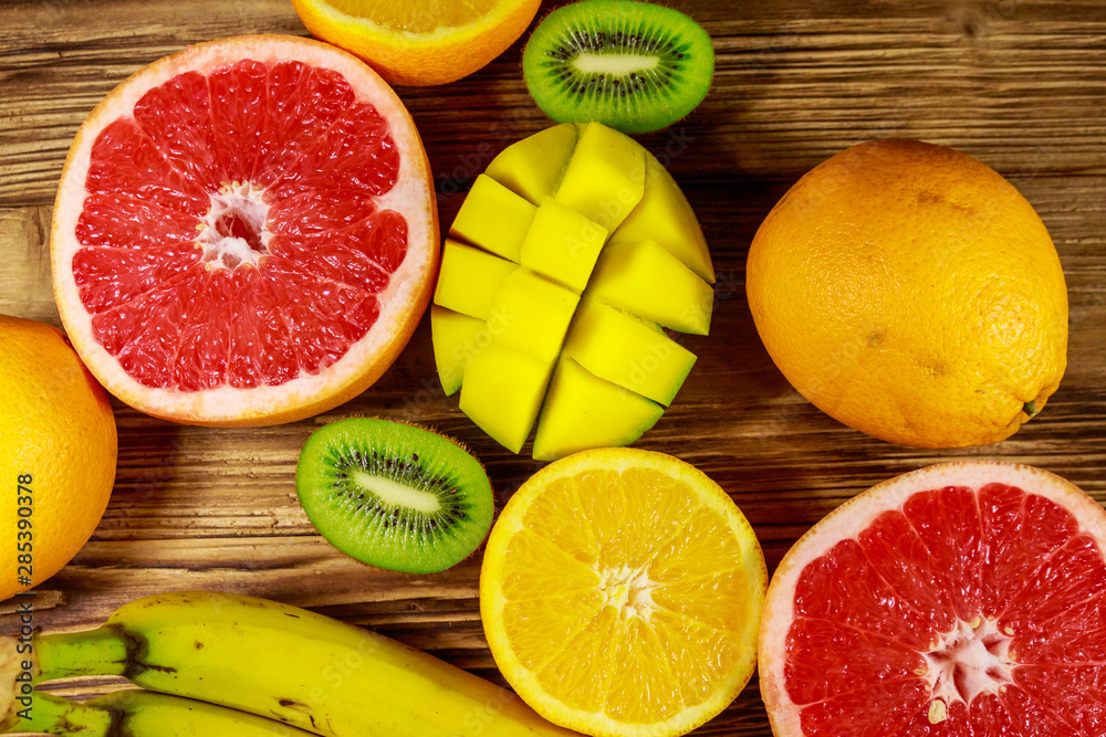 Assortment of tropical fruits on wooden table. Still life with bananas, mango, oranges, grapefruit and kiwi fruits Assortment of tropical fruits on wooden table. Still life with bananas, mango, oranges, grapefruit and kiwi fruits