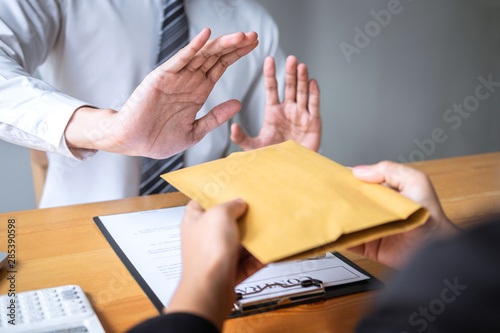 Anti bribery and corruption concept, Business man refusing and don't receive money banknote in envelope offer from business people to accept agreement contract of investment deal photo