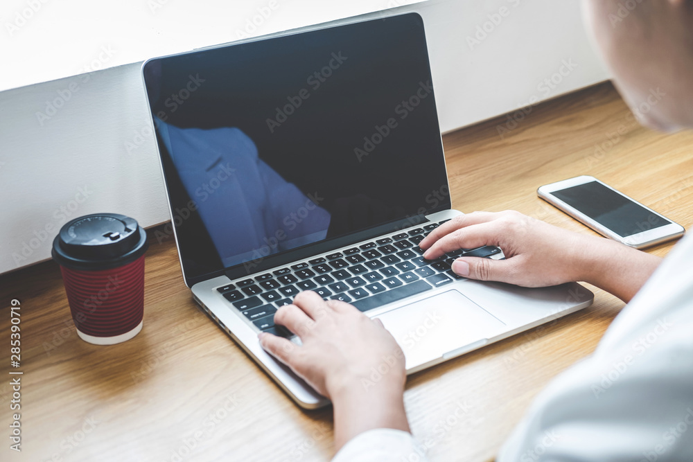 Image of Young woman working in front of the laptop looking at screen with a clean white screen and blank space for text and hand typing information on keyboard in modern workspace Image of Young woman working in front of the laptop looking at screen with a clean white screen and blank space for text and hand typing information on keyboard in modern workspace