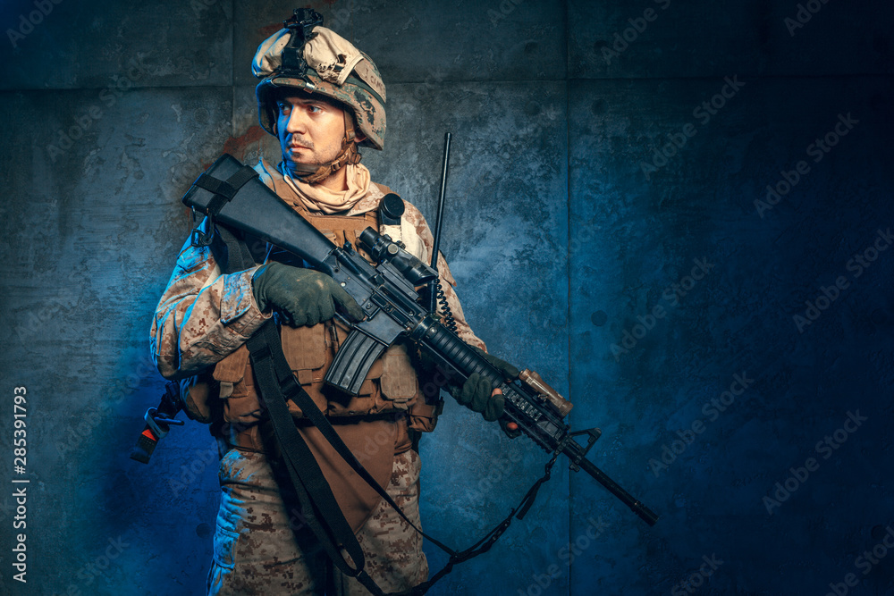 Young man in military outfit a mercenary soldier in modern times on a dark background in studio