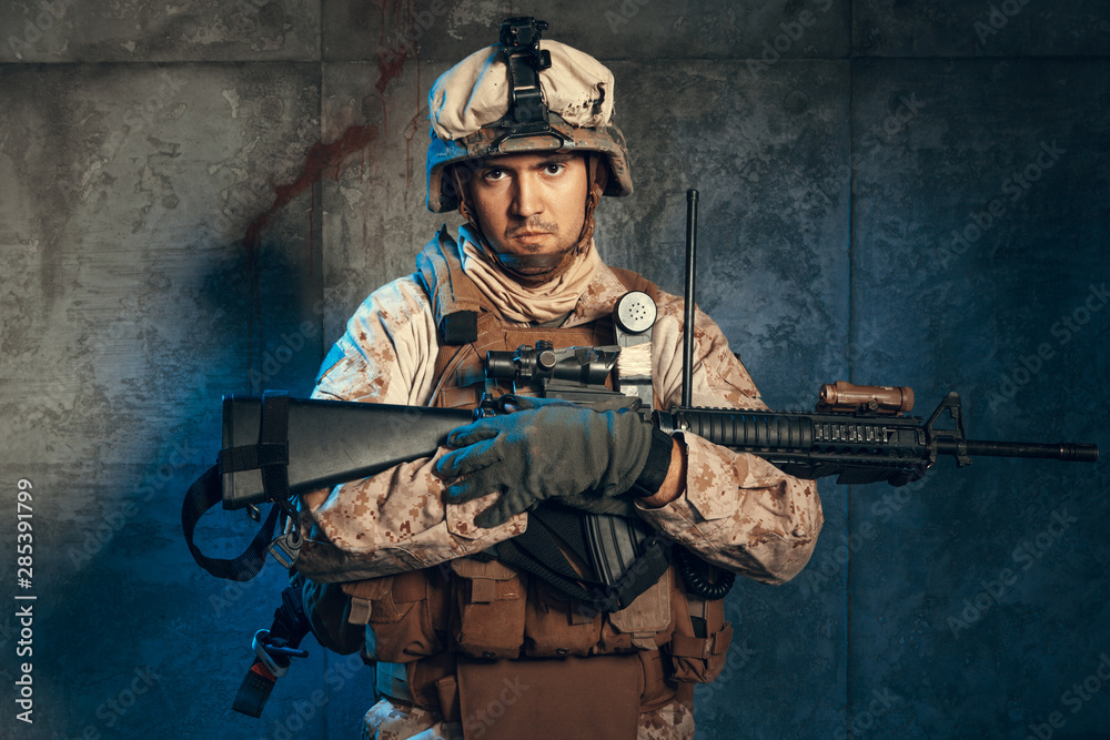 Young man in military outfit a mercenary soldier in modern times on a dark background in studio Young man in military outfit a mercenary soldier in modern times on a dark background in studio
