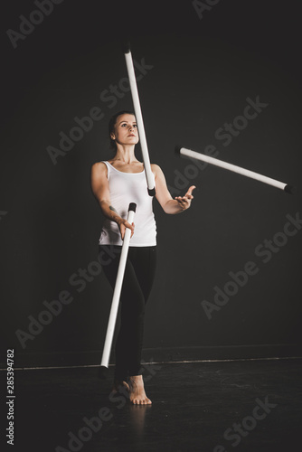 Juggler girl on black background, woman training 