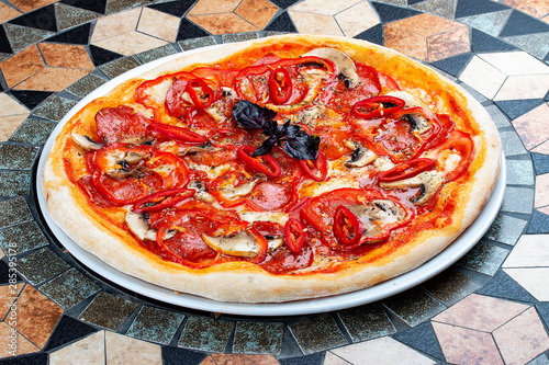 Diabola pizza with chorizo and chili. Spicy dish. On the stone table photo