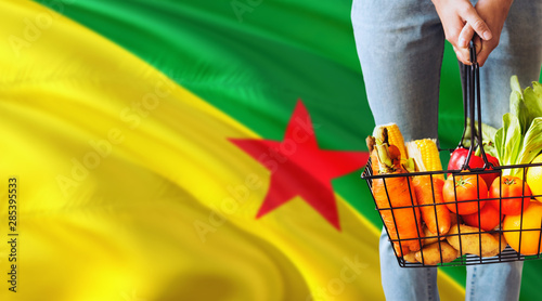 Fotografi Woman is holding supermarket basket, French Guiana waving flag background