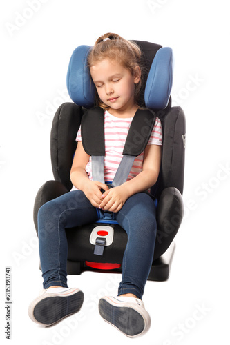 Sleeping little girl buckled in car safety seat on white background