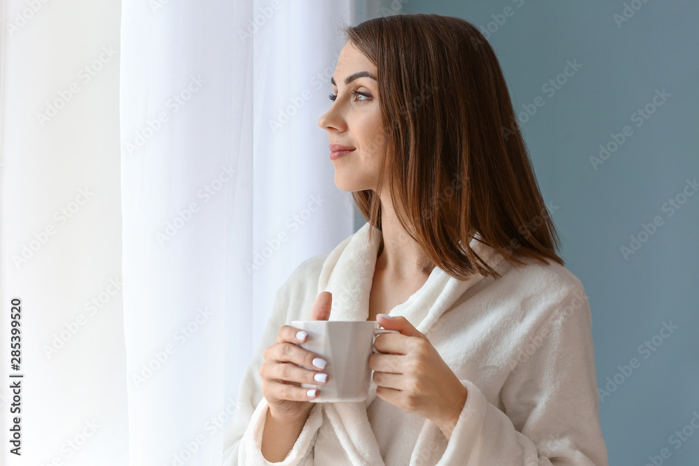 Beautiful young woman drinking tea near window Beautiful young woman drinking tea near window