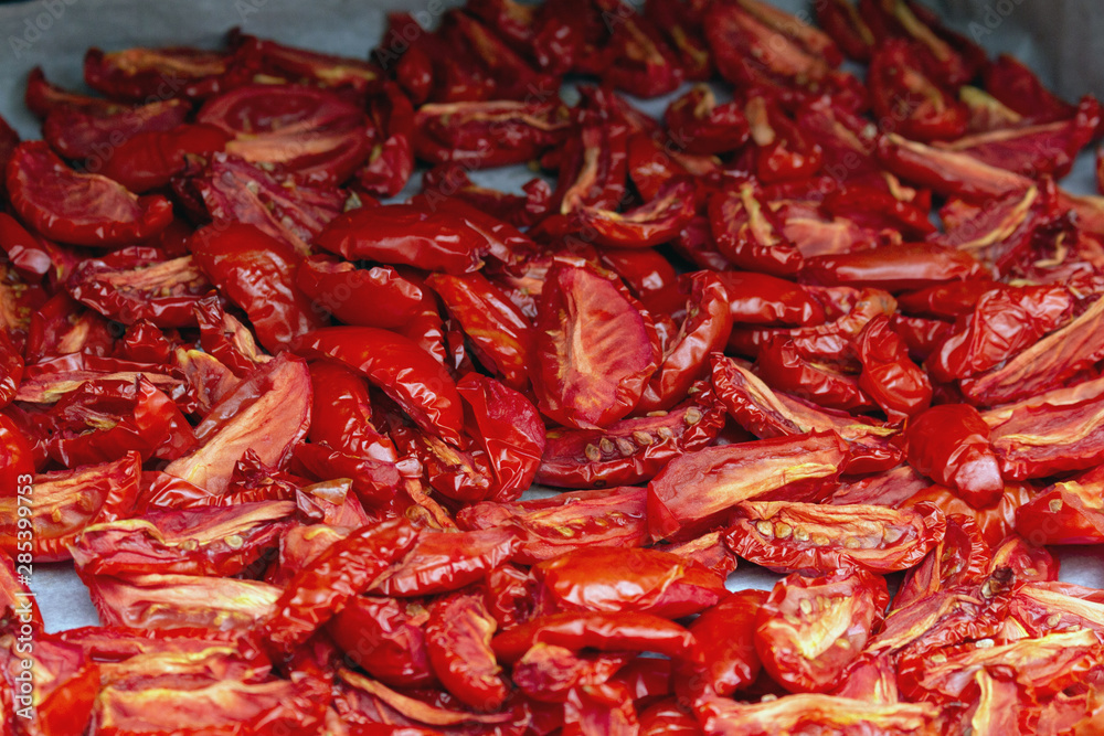 Homemade dried red tomatoes slices with basil oregano spices cooking process. Traditional Italian Mediterranean kitchen cuisine. Homemade dried red tomatoes slices with basil oregano spices cooking process. Traditional Italian Mediterranean kitchen cuisine.