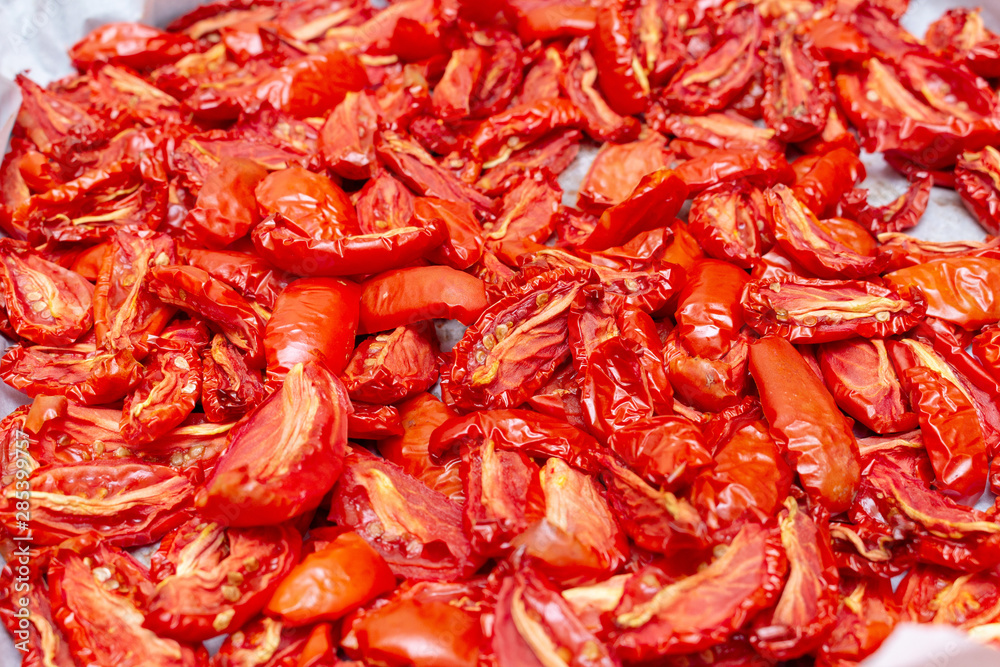 Homemade dried red tomatoes slices with basil oregano spices cooking process. Traditional Italian Mediterranean kitchen cuisine. Homemade dried red tomatoes slices with basil oregano spices cooking process. Traditional Italian Mediterranean kitchen cuisine.