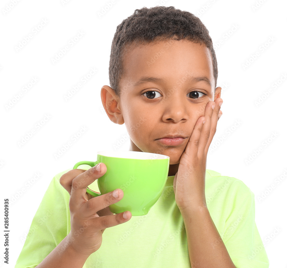 Little African-American boy with sensitive teeth and cup of tea on white background